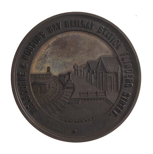 Round medal with railyard scene, text around,
