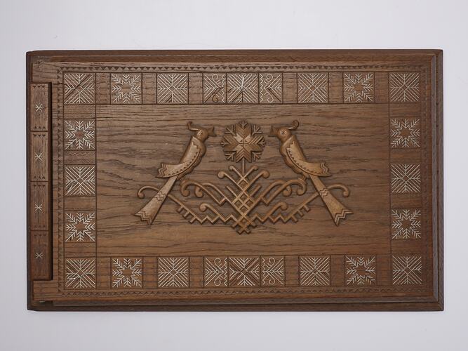 Rectangular wooden album cover intricately carved with two central birds framed by square patterned border.