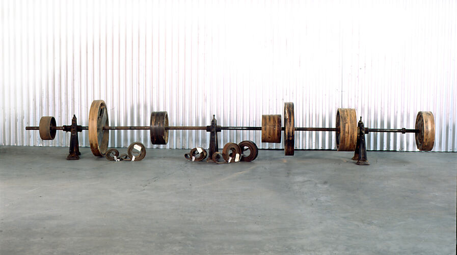 Long metal pipe with wooden pulleys along its length.