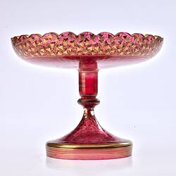 Red glass base/stand of epergne. Shaped like one piece plate on stand. Gilded decoration.