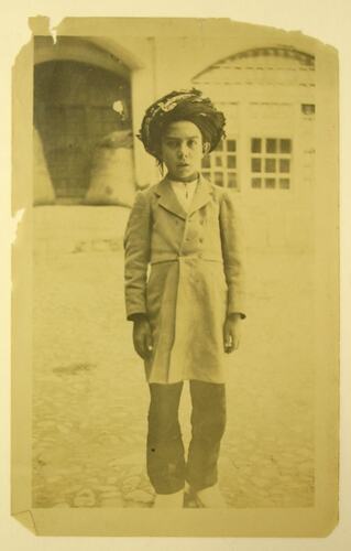 Boy wearing traditional clothing, posed for camera.