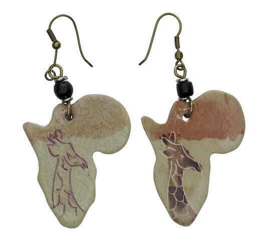 Stone earrings shaped like Africa with giraffes painted on them.