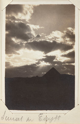 View of a pyramid with cloudy sky and ground in shadow.