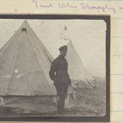 Soldier standing next to Tent, with a second tent behind.