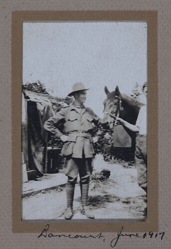 Man in military uniform standing next to a man holding a horse's bridle.