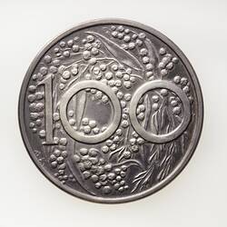 Round silver coin with cluster of wattle. The number 100 superimposed over the wattle.