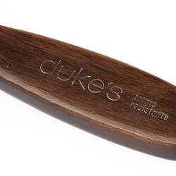 Detail of wooden hairbrush handle with imprinted text.
