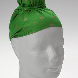 Topknotted green headscarf with decorative gold stamp design.