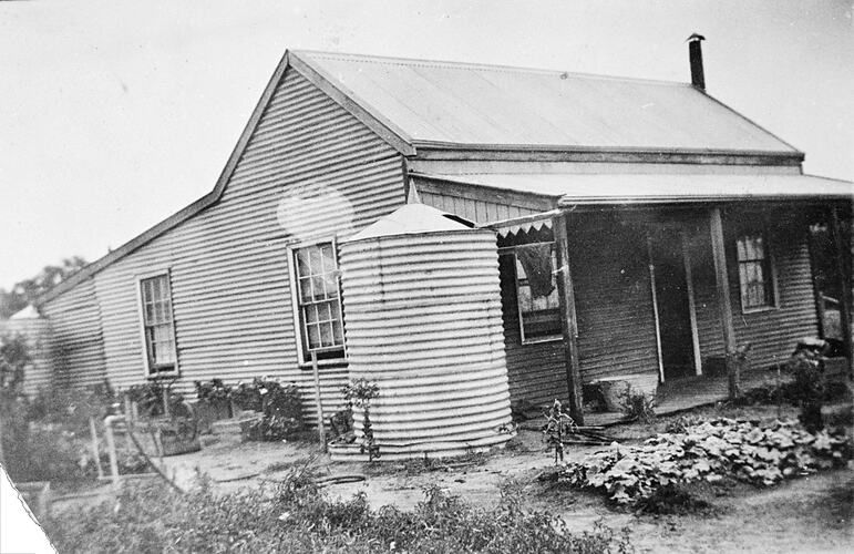 Corrugated iron farm house, two large water tanks and a flower garden.