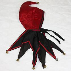 Red and black jester's hat. The peaked cap is red and collar section black. Each peak has a bell.