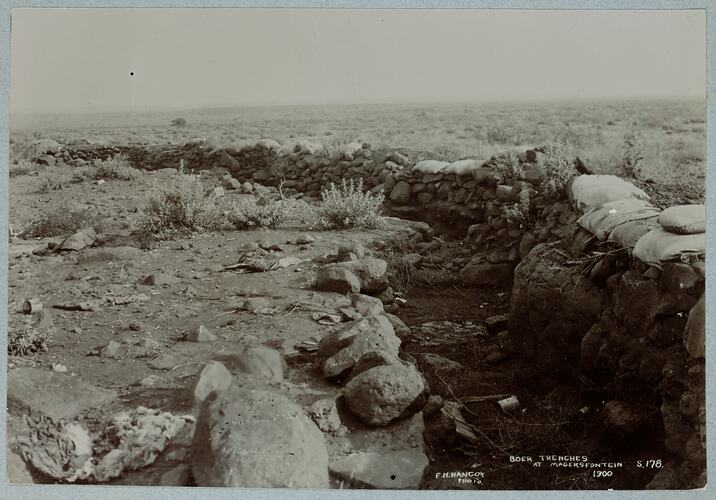 Flat grassy landscape with wall of sandbags.