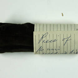 Rolled piece of brown velvet with note around.