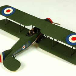 Dark green aeroplane model with red, white, blue circles on wings. Three quarter view from rear right side.