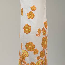 Back of long sleeveless white cotton dress. Orange and yellow floral printed pattern.