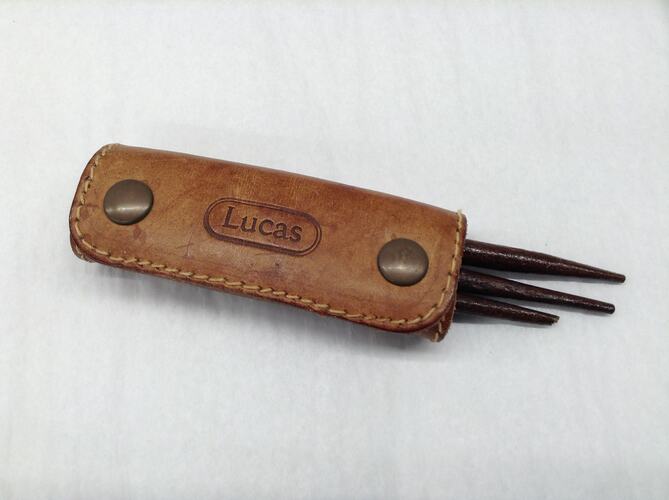 Brown leather sheath with wooden implements inside.