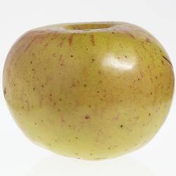 Wax model of an apple painted yellow with red flecks.