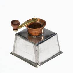 Miniature coffee grinder made from silver and copper. Brass handle on top.