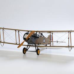 Model biplane aeroplane painted mustard brown with grey engine. Three quarter left view.