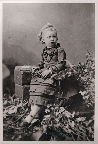 Young girl posing, sitting amongst leaves.