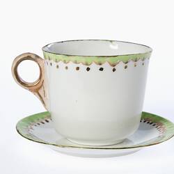 White porcelain tea cup and saucer. Green, pink and gold formal decoration trim.