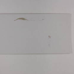Plain back of a brown exhibition label.