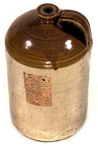 Pottery jar - handle, no cork, handwritten label.