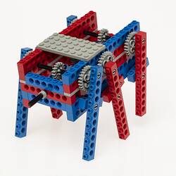 Red, blue and grey LEGO robot with three legs either side. Back.