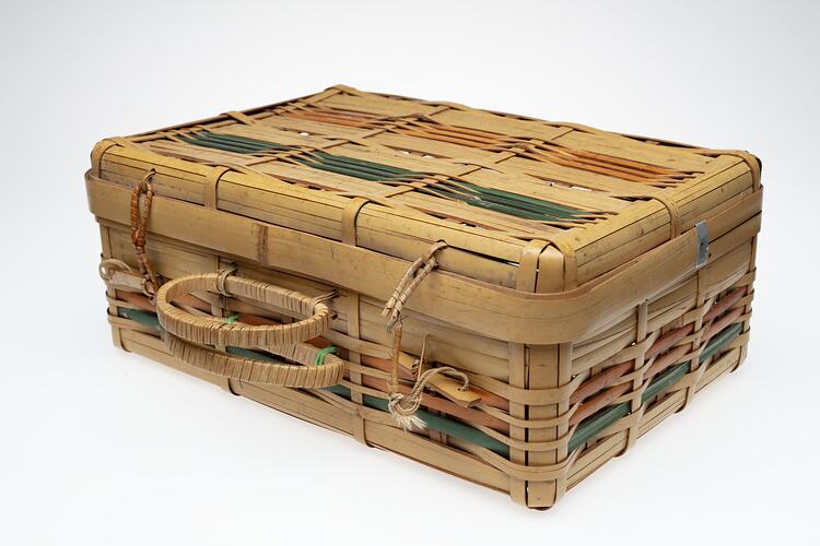 Split cane basket, hinge lid. Orange and green stripe detail. Two handles at front.