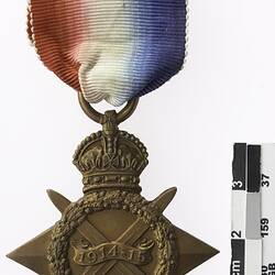 Four pointed star shaped medal with crown above crossed swords and wreath, with red, white and blue ribbon.