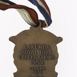 Bronze medal with text, red, white and blue ribbon attached.