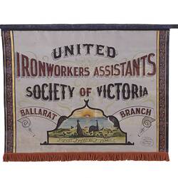 Rectangular canvas banner painted white with coloured text. Has kangaroo and emu emblem.