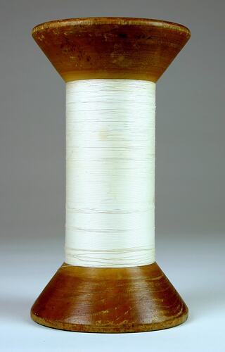 A reel of  thread on a wooden spool.