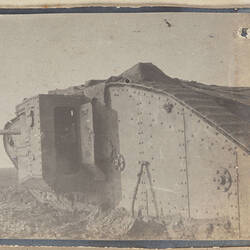 Close up of left side of tank in field with gun and entry hatch.