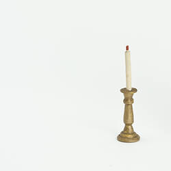 Doll's house gold candlestick with white taper candle.