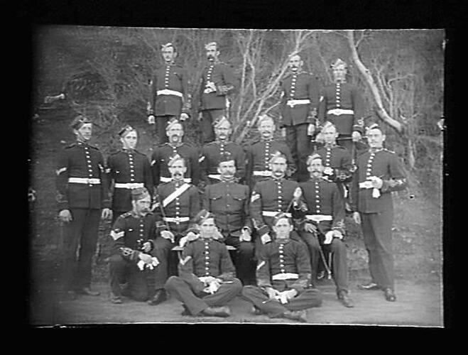 Military personnel of 18 men posed in formal group portrait.
