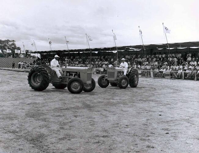Two tractors on display in front of grandstand.