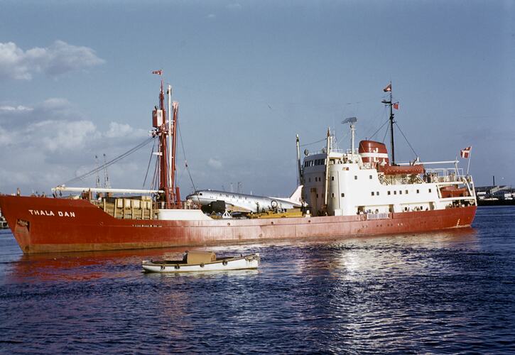Red ship with aeroplane as cargo.