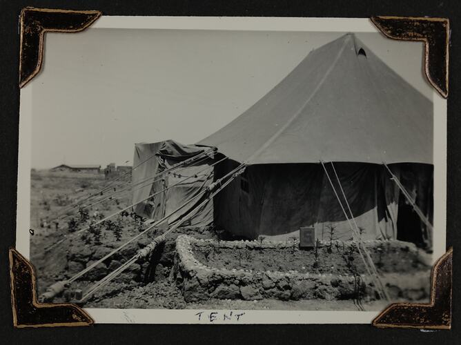 Exterior view of a tent, with garden bed next to tent opening.