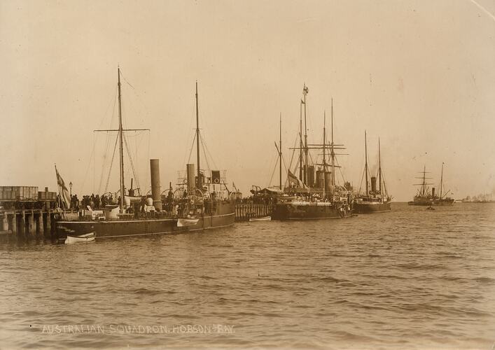 Sailing ships moored at a wharf.