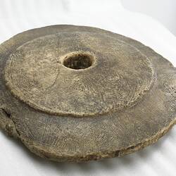 Round irregular brown stone disc with central hole.
