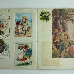 Open scrapbook page with various cards showing depictions of scenery, children and farmland.