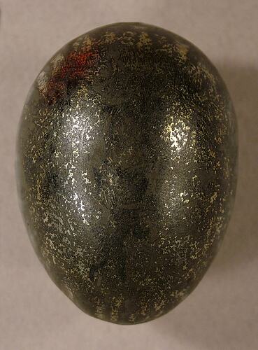 Metal hen egg with worn gold surface.