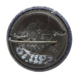 Back of round metal badge with horizontal pin.