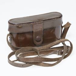 Back of dark tan leather camera case with shoulder strap.