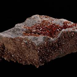 Red-orange crystals on grey rock.