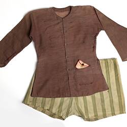 Brown shirt with pink silk purse in pocket, striped shorts.