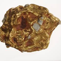 Gold nugget replica with grey bits embedded in it.