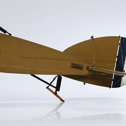 Model biplane aeroplane painted mustard. Tail detail. Blue, red white rondel on side and stripes on rudder.