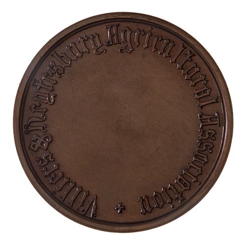 Round bronze medal with central blank section for engraving. Text around edge.