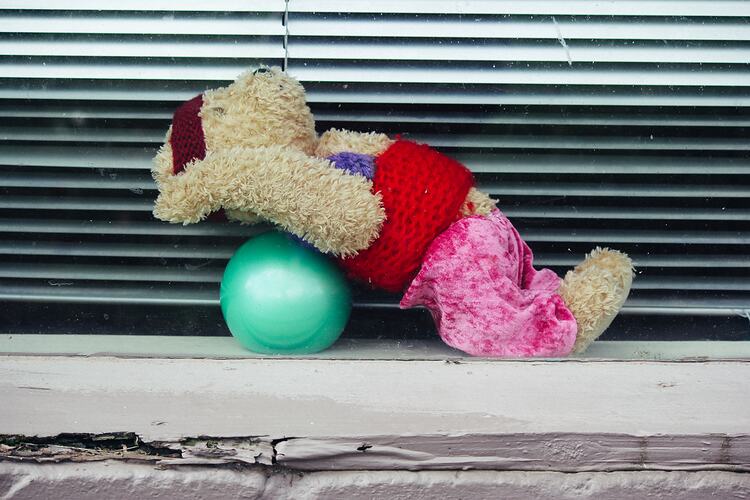 Yoga teddy on green ball placed in window.